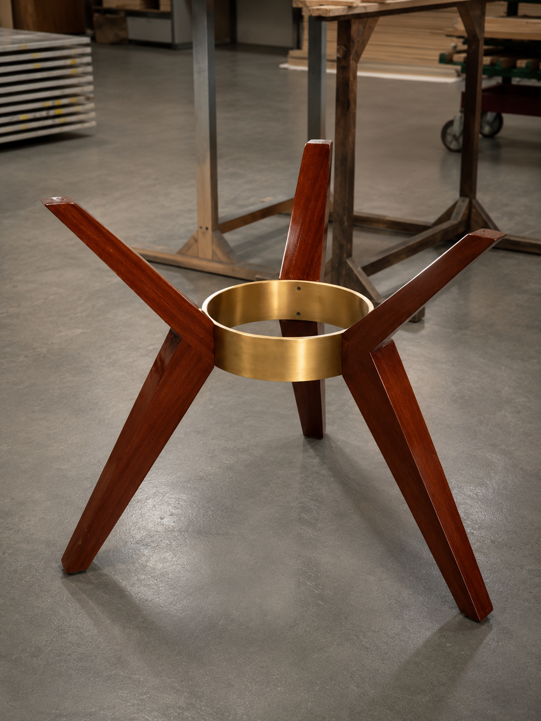 Custom spider-leg table base in solid mahogany with machined brass collar — workshop fabrication
